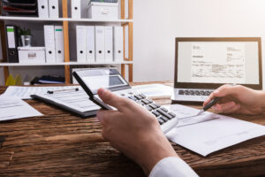 An individual holding a calculator and carefully budgeting their finances