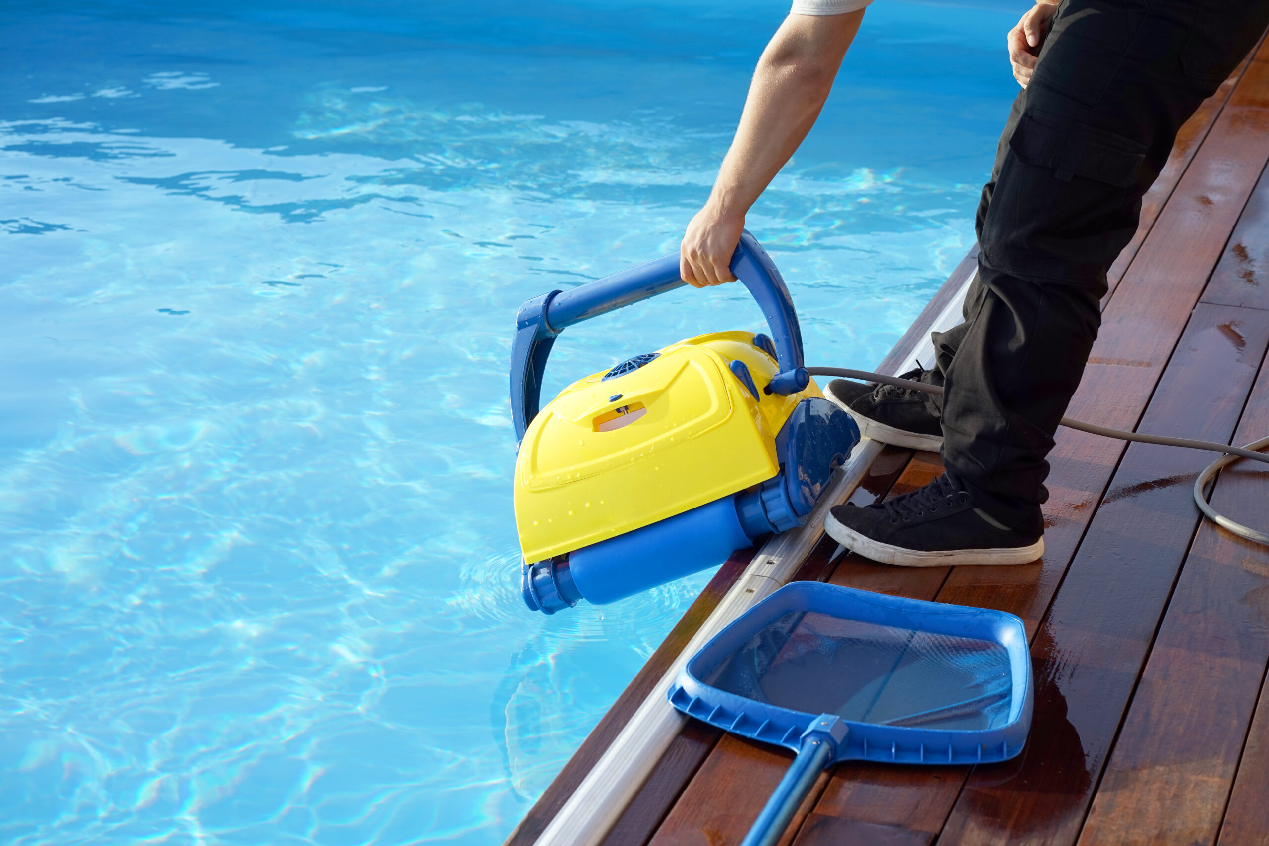 Man holding a pool vacuum or brush machine, ready to clean the pool's surface