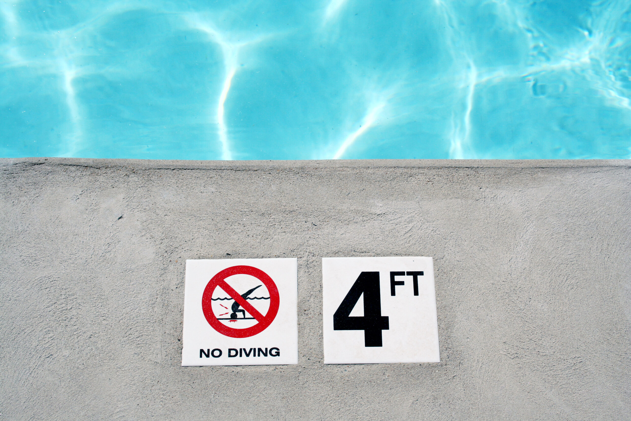 Signage by a pool indicating a depth of 4 feet and prohibiting diving, ensuring safety for pool users.