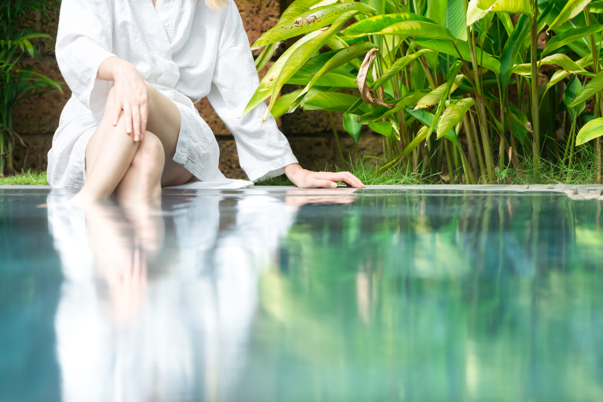 A relaxed woman sitting on the edge of a pool