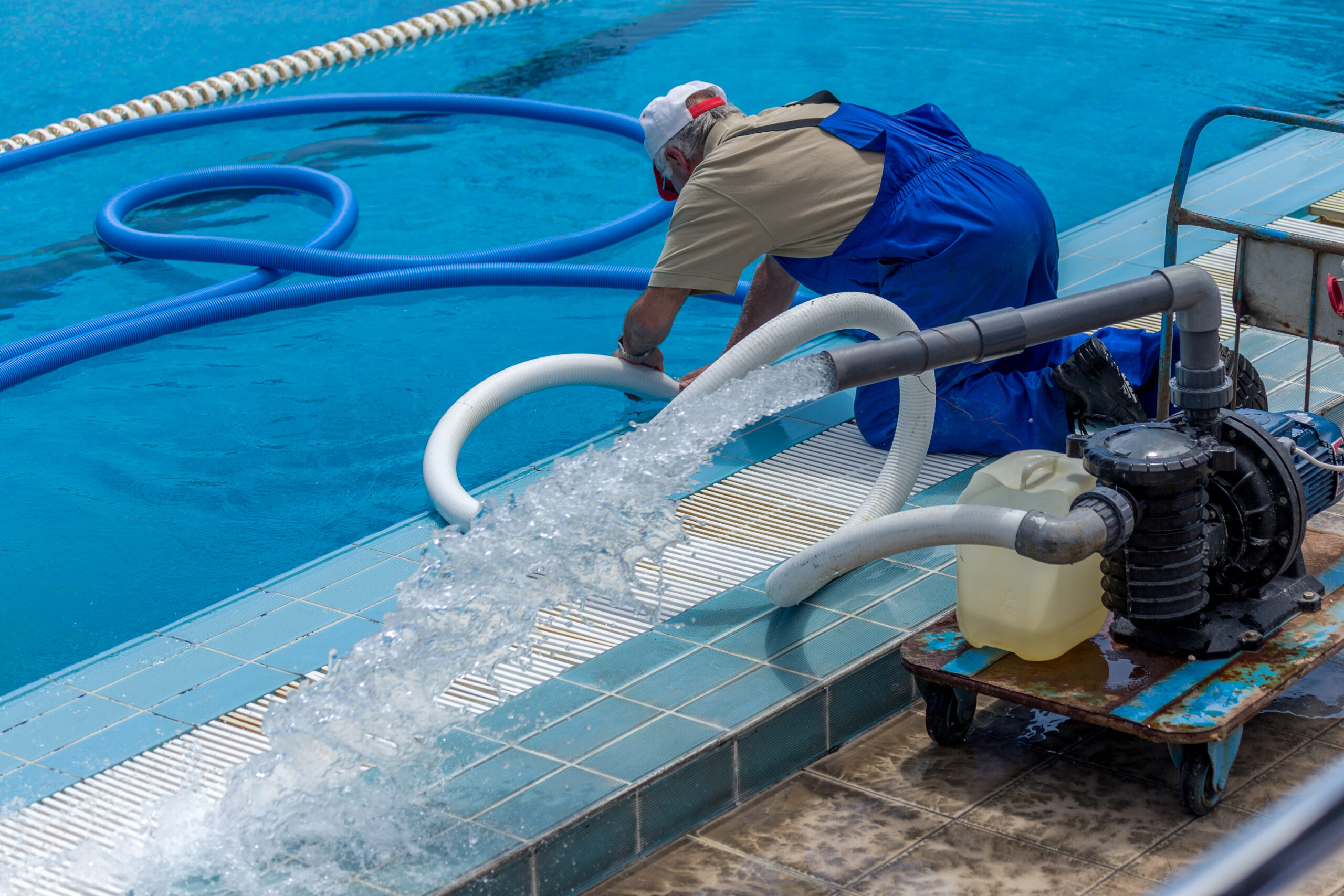 A man actively cleaning and maintaining a swimming pool, utilizing a filtration system to ensure the water remains clean and clear, and the pool area remains enjoyable.
