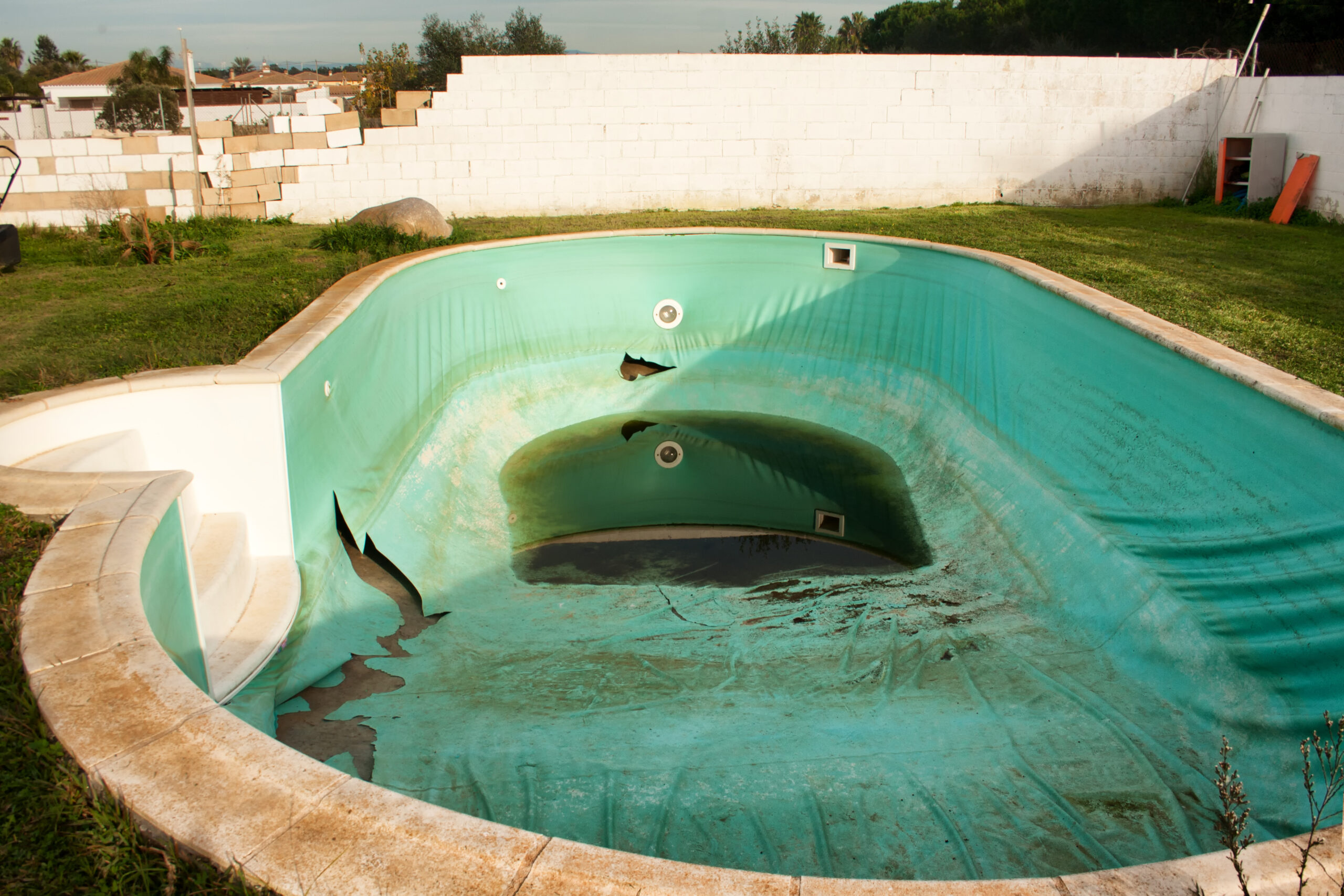 A pool in a state of disrepair and dirtiness, with visible damage and a buildup of debris and algae, requiring thorough cleaning and restoration