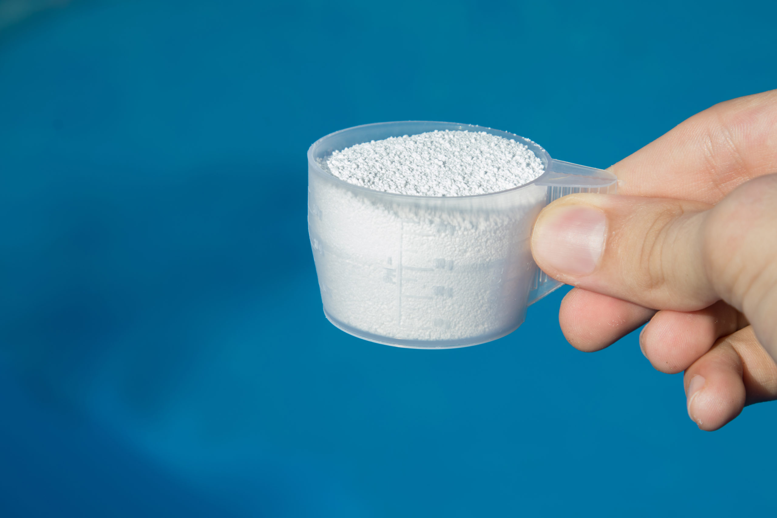 A small cup containing chlorine granules, typically used for pool water treatment and disinfection.