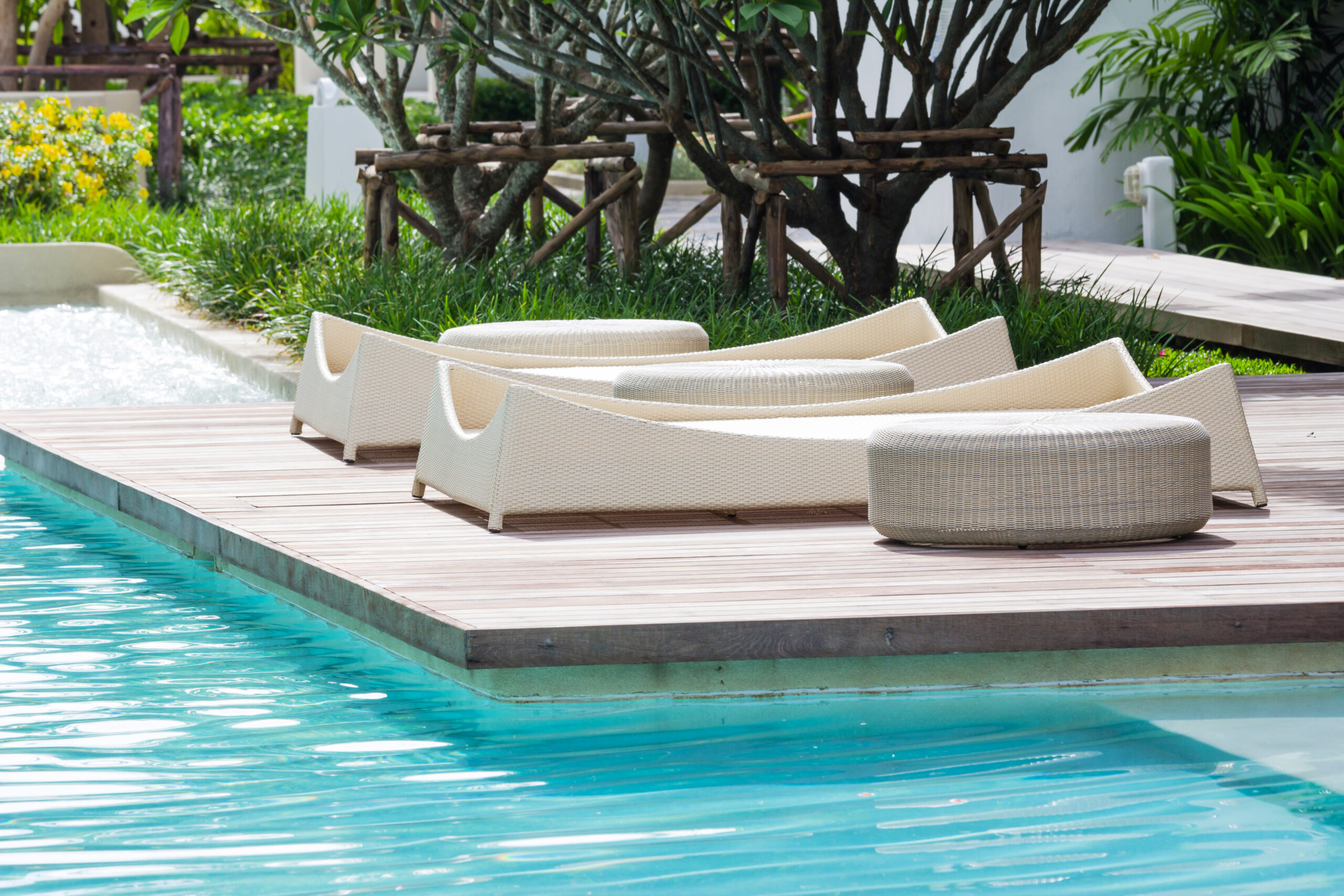 White chairs and lounge beds arranged by the pool, offering comfortable seating and relaxation options for poolside guests.