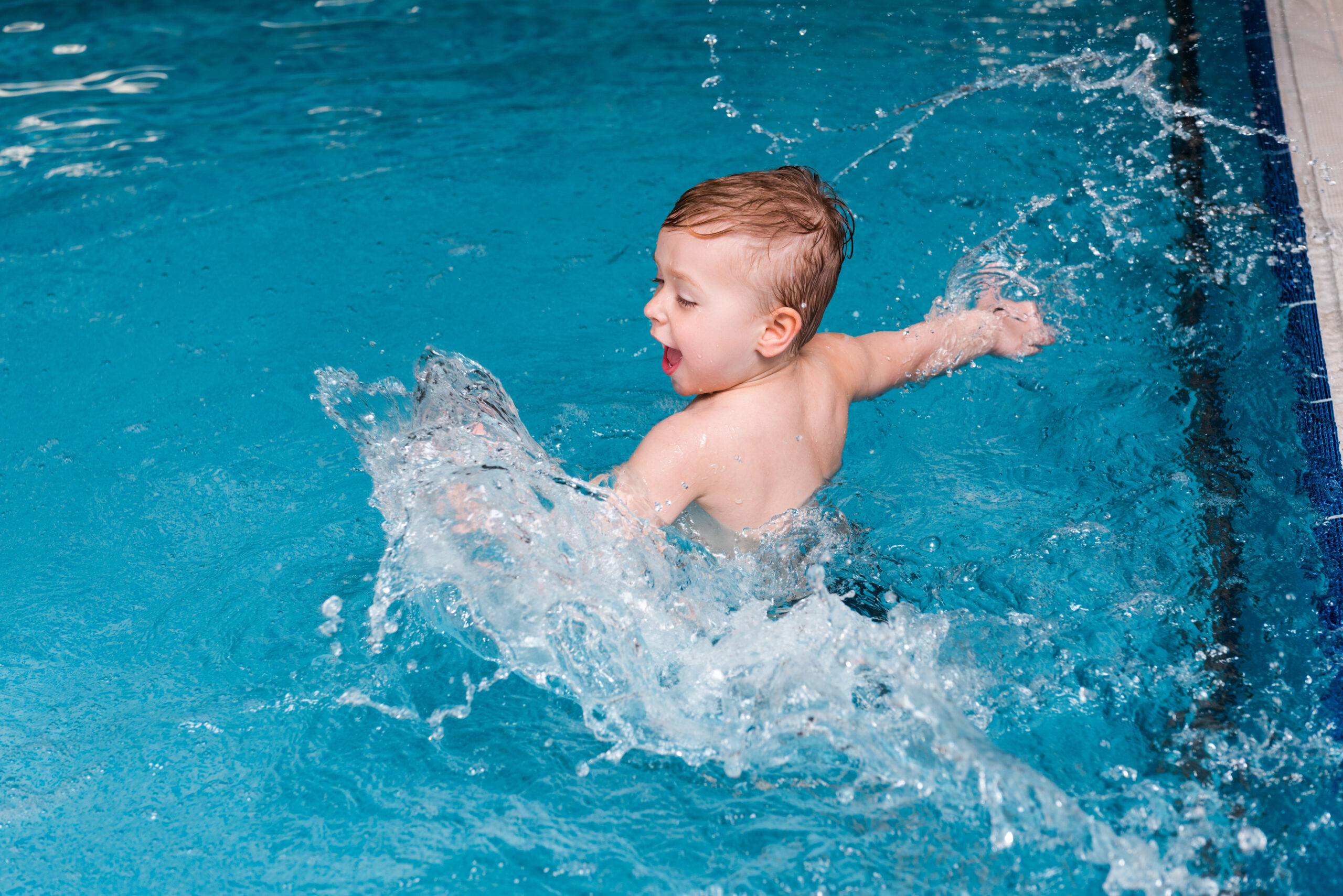 A baby in a swimming pool, gleefully splashing and enjoying their first experiences in the water