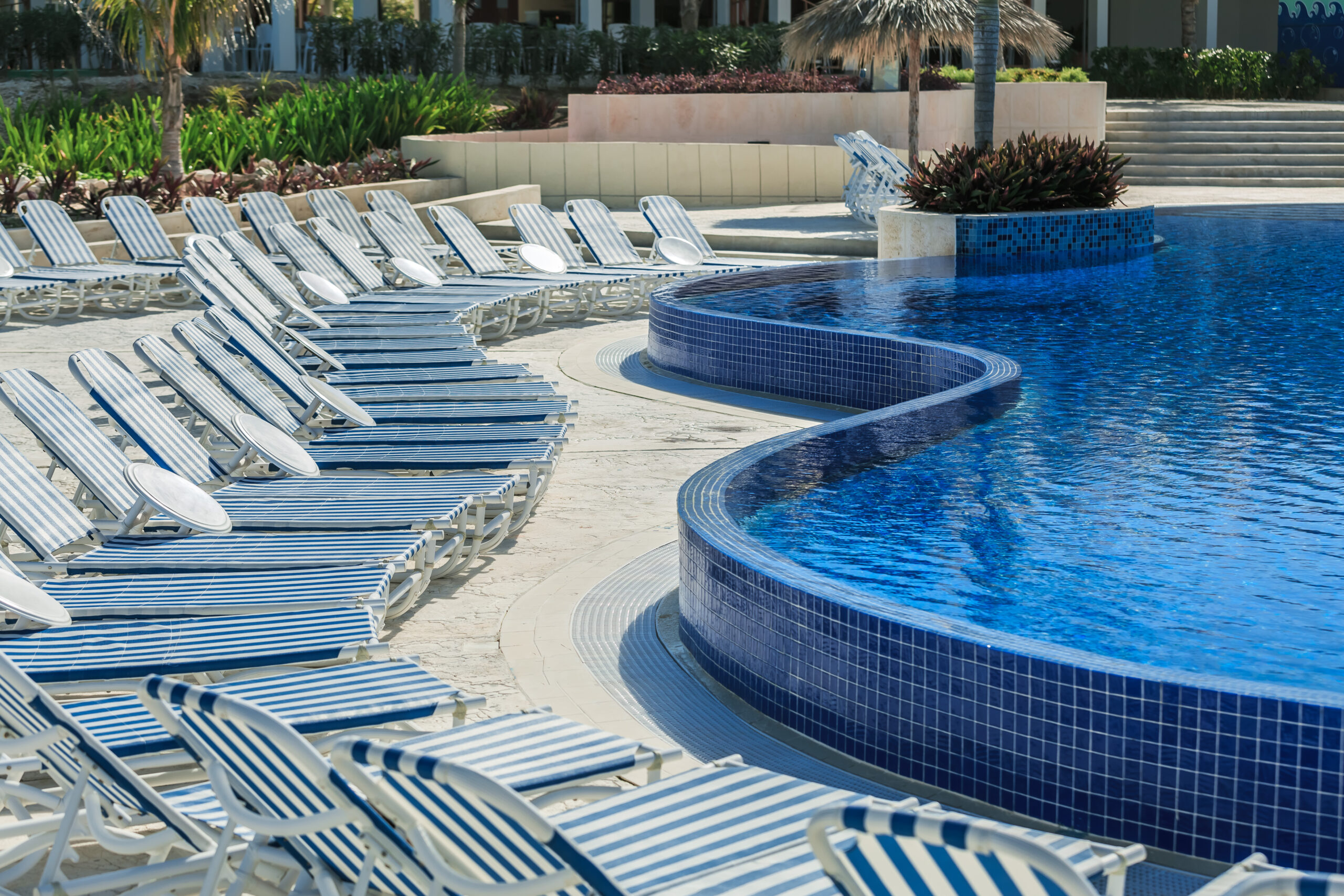 Poolside chairs arranged beside glistening pool tiles, creating an inviting space for relaxation.