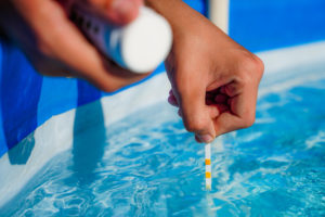 Checking the water quality of a pool with the help of a test strip with PH value, chlorine and algaecide. High quality photo