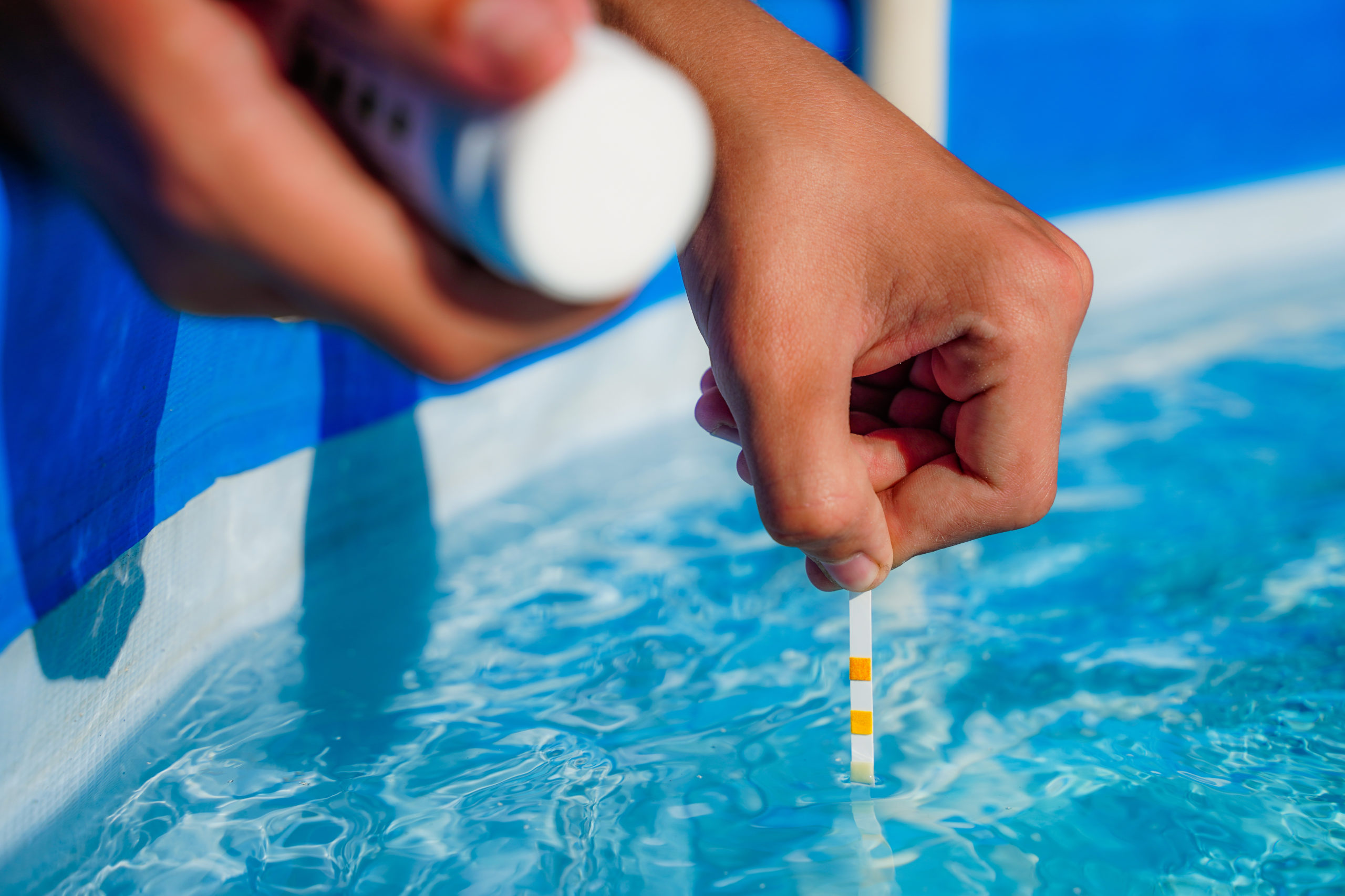 Testing the pH level of a swimming pool water using a pH testing ki