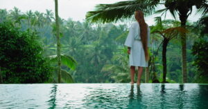 Long-haired girl enjoys the morning in rice terraces tropical forest nature background. Woman with thick and healthy hair. Summertime nature paddy field. Outdoor landscape.