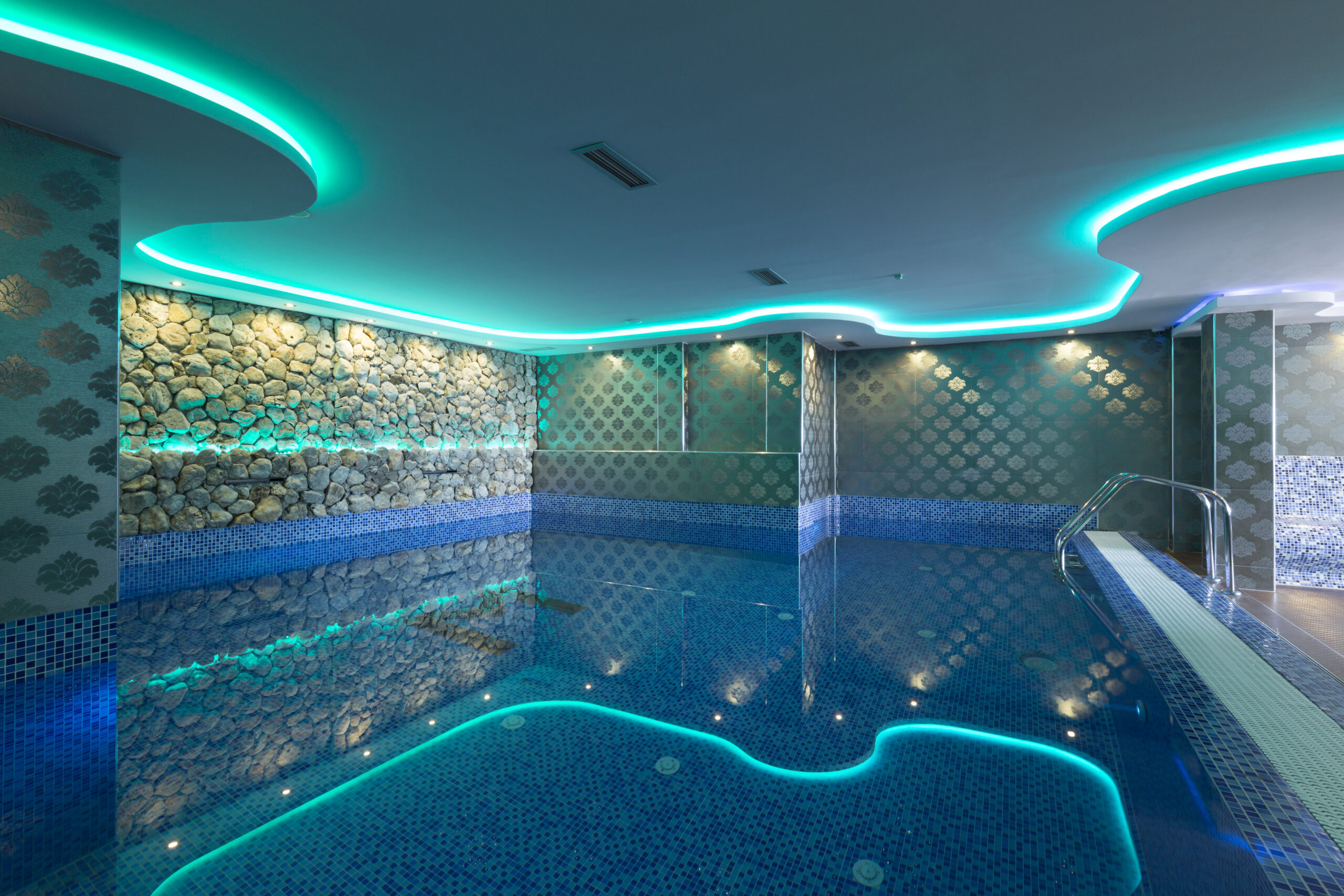 An indoor pool featuring both underwater and above-water lights, creating a visually stunning and inviting atmosphere.