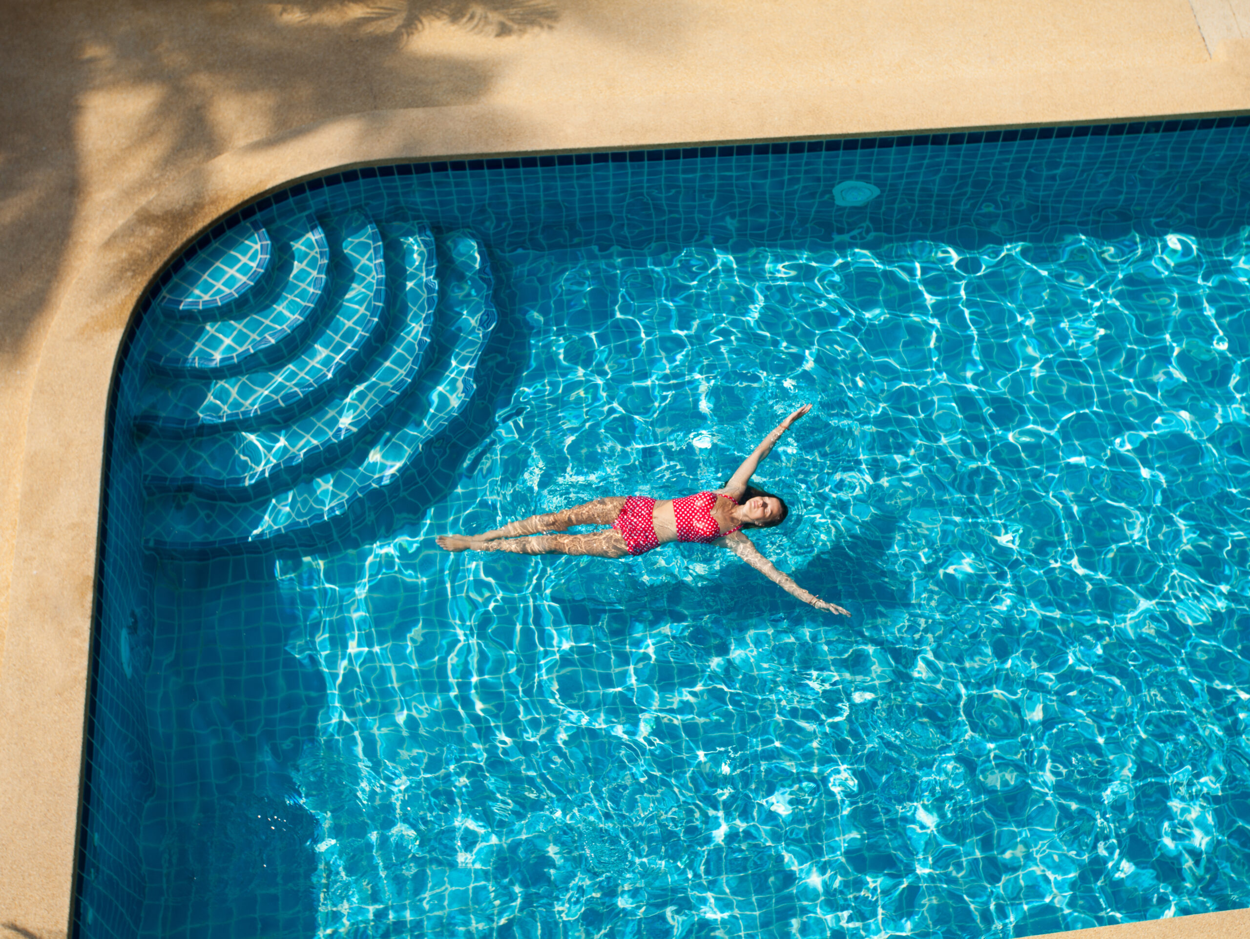 A woman relaxing while floating in a pool, enjoying a peaceful and leisurely moment in the water.