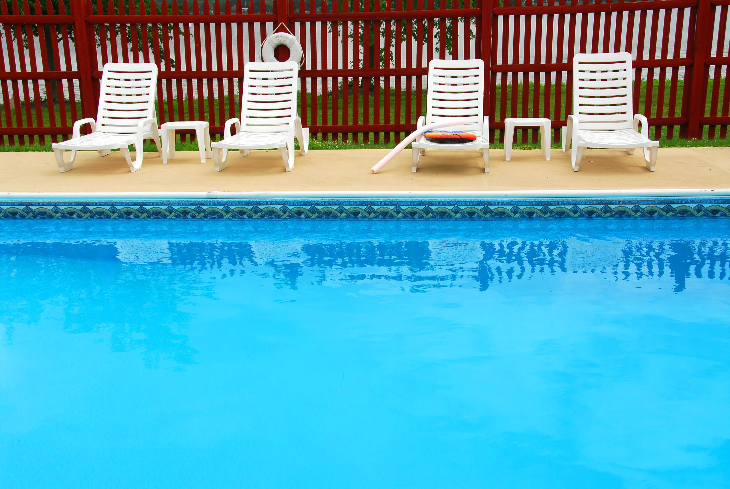 White chairs arranged on the pool deck, providing comfortable seating for poolside relaxation.
