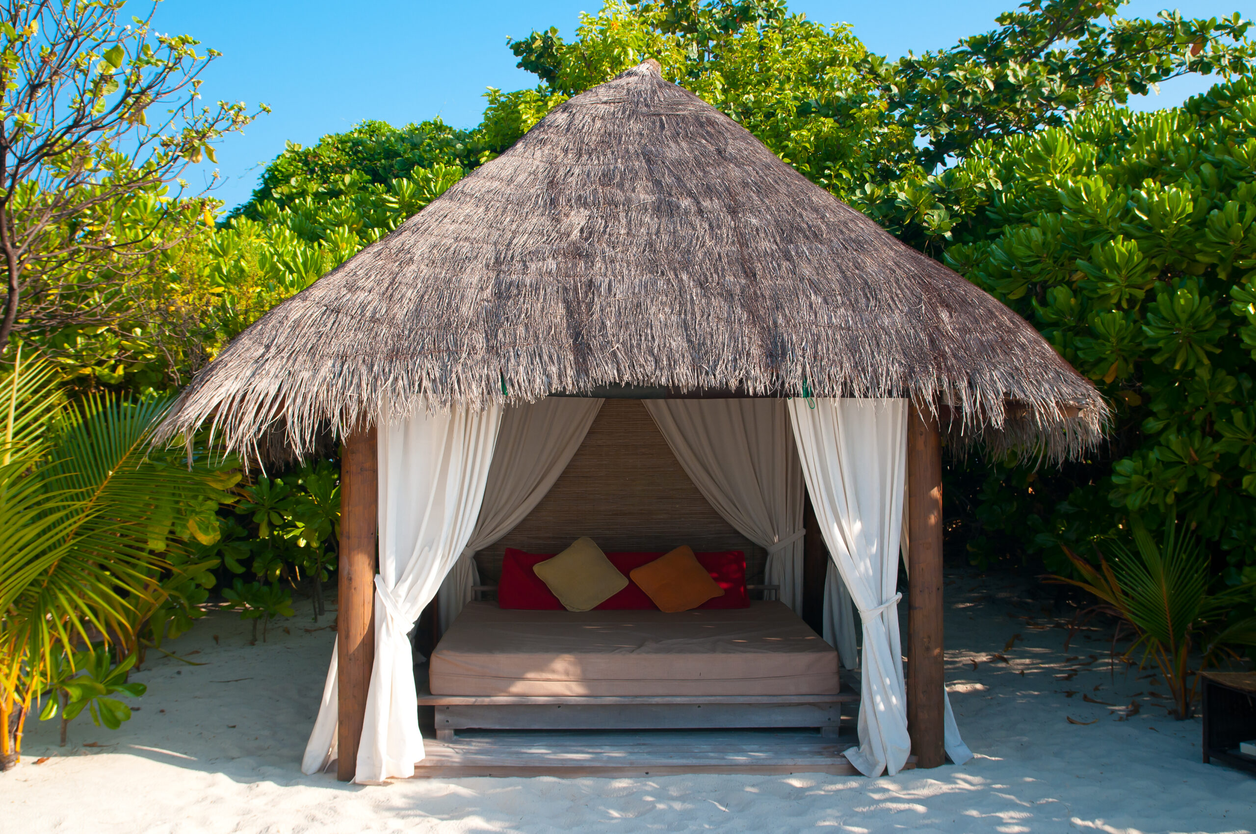  A quaint, small cabana with a thatched roof and a few lounge chairs