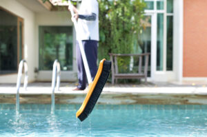 Man is cleaning a swimming pool with a brush