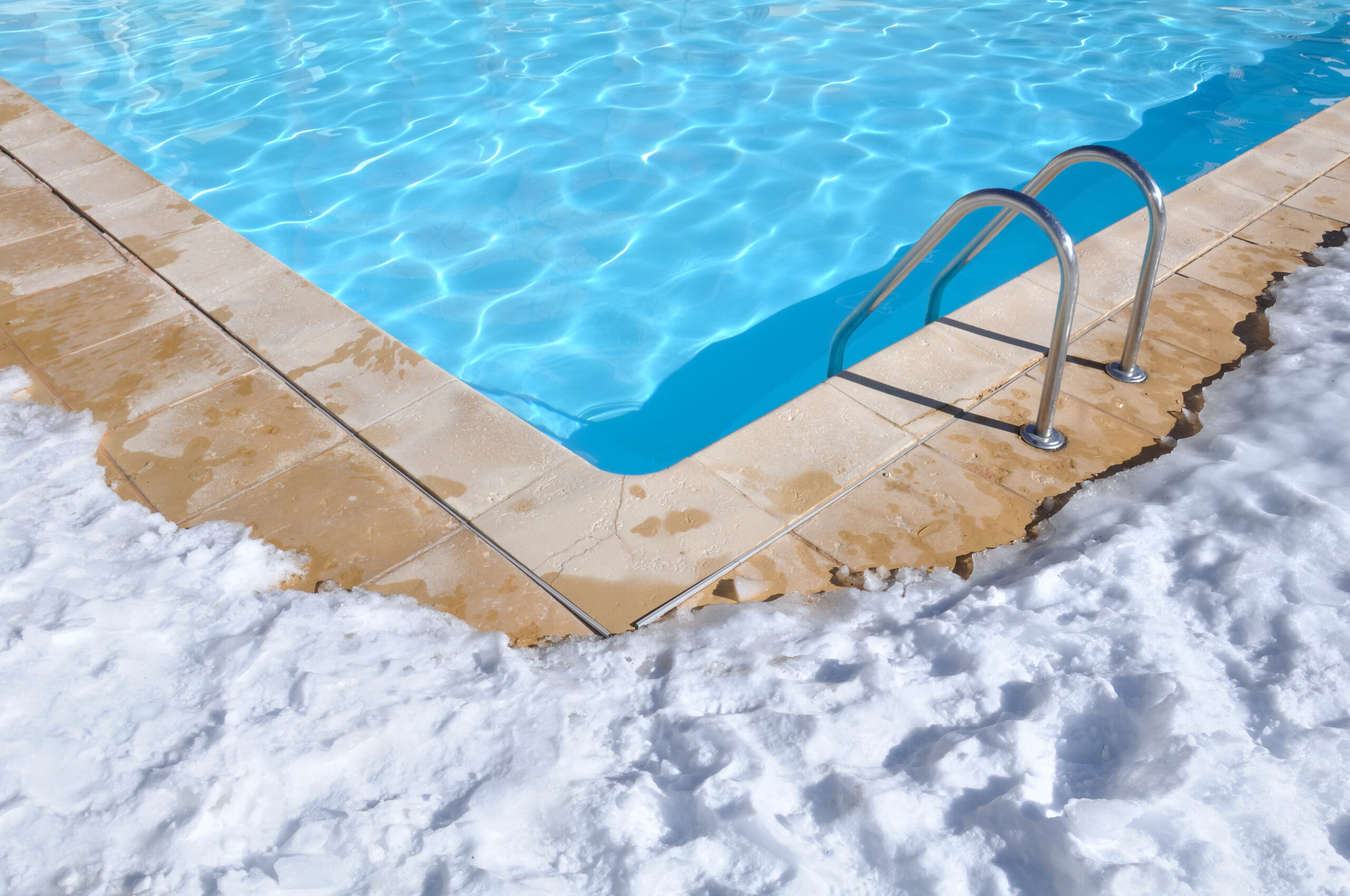 A swimming pool with a layer of snow at its edge