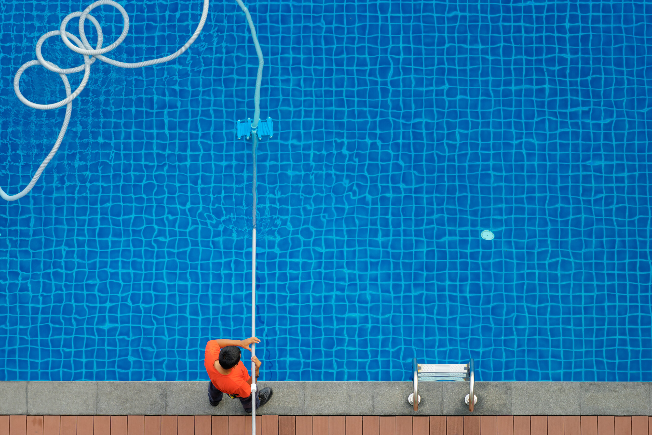 a man using cleaning tool to clean the pool